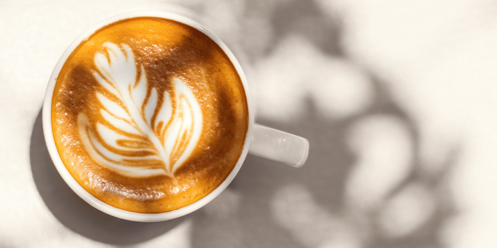 eine Tasse Cappuccino mit Latteart steht auf einem weißen Untergrund