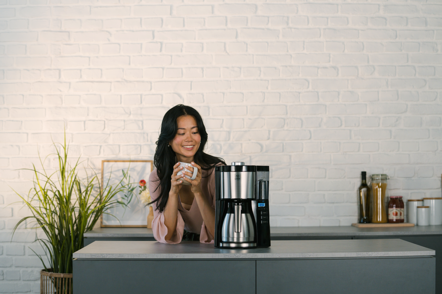 Melitta LOOK Therm Timer Filterkaffeemaschine mit Isolierkanne auf einer Küchenarbeitsplatte, mit einer Person im Hintergrund.