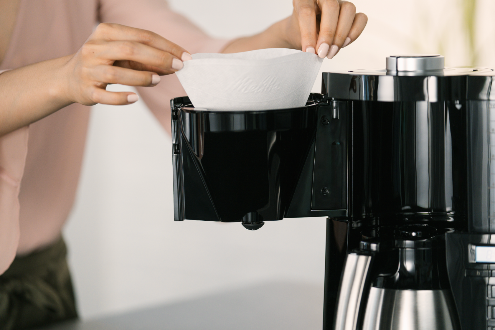 Nahaufnahme, wie ein Kaffeefilter aus Papier in den Filterhalter der Melitta® LOOK® Therm Timer Filterkaffeemaschine eingesetzt wird.