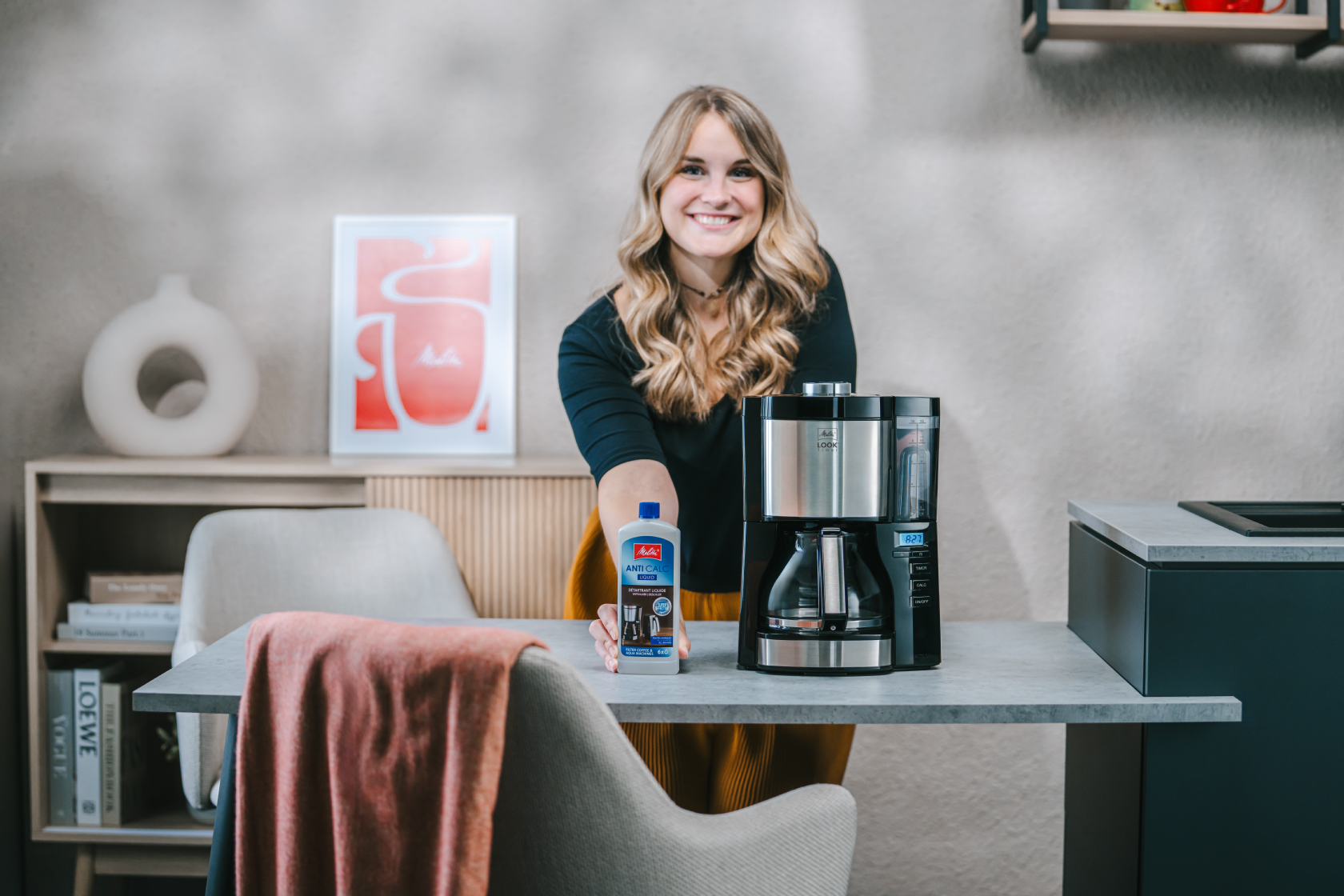 Frau mit Melitta® Anti Calc neben der Melitta® LOOK® Timer Filterkaffeemaschine