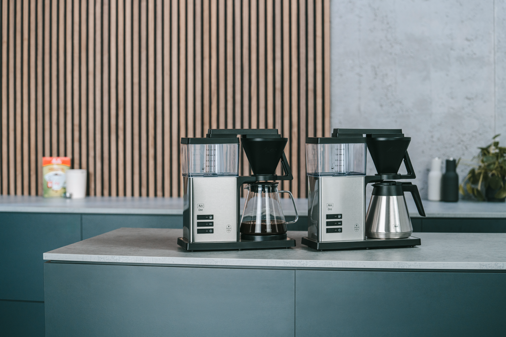 Zwei Filterkaffeemaschinen mit Glaskannen auf einer Küchenarbeitsplatte in einer modernen Küche.
