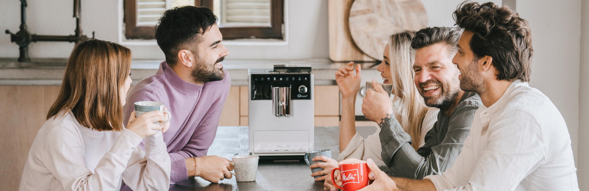 Freundesgruppe genießt Kaffee mit einer weißen Melitta CI Touch auf dem Tisch