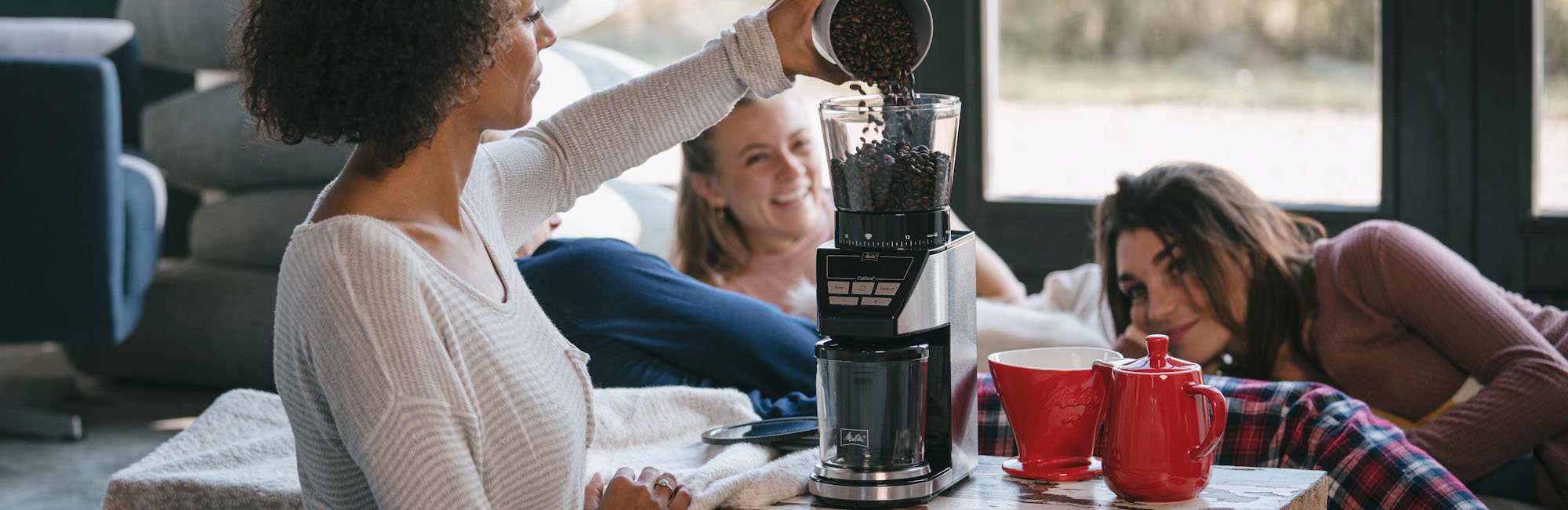 Image of a person pouring coffee into our coffee grinder named Calibra