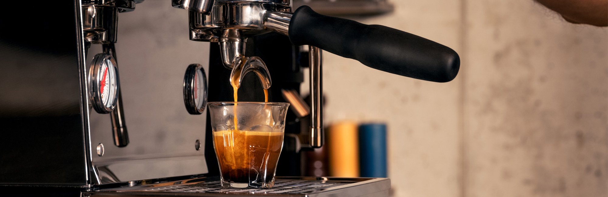 Siebträger Maschine bereitet einen Espresso zu, Espresso läuft in ein Espressoglas