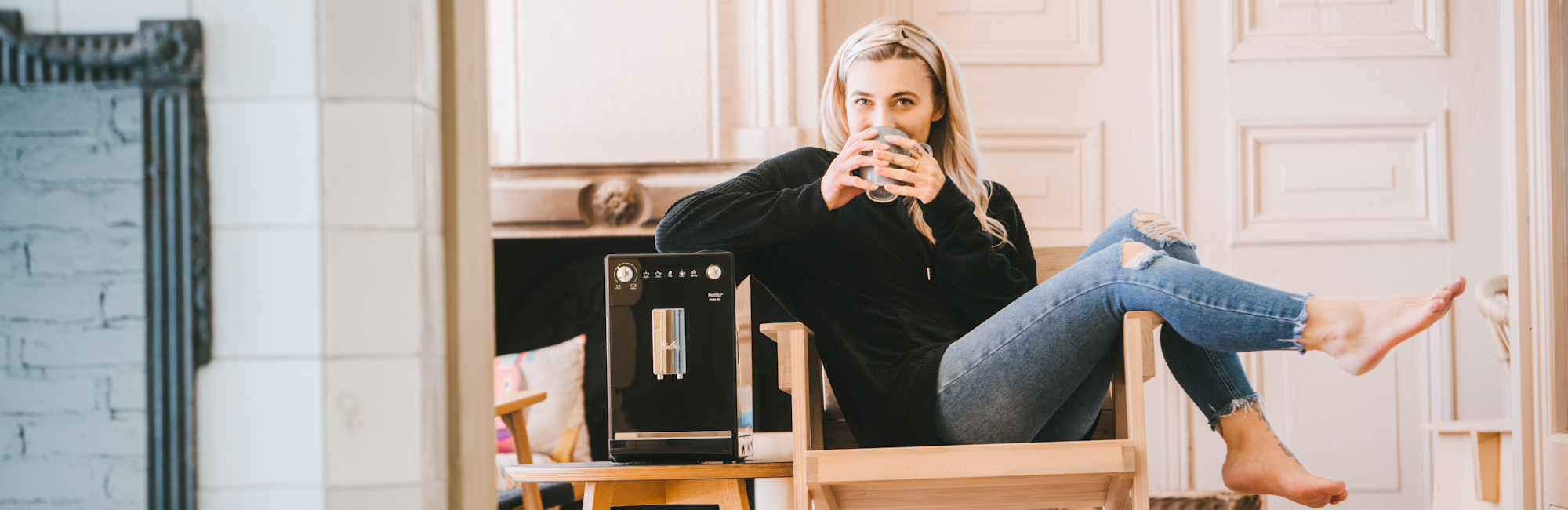 Eine Frau sitzt auf einem Holzstuhl und genießt ihren Melitta Kaffee