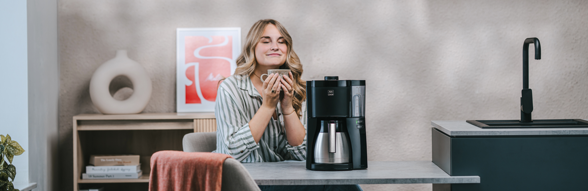 Frau genießt Kaffee neben der Melitta® LOOK® Therm Filterkaffeemaschine