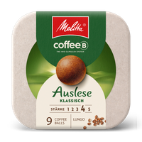 Kaffeetasse aus Glas gefüllt mit Kaffee vor Verpackung der Melitta® Auslese klassisch coffeeb Verpackung