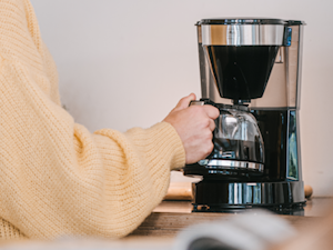 Hand entnimmt die Glaskanne aus einer schwarzen Melitta Easy Top Filterkaffeemaschine