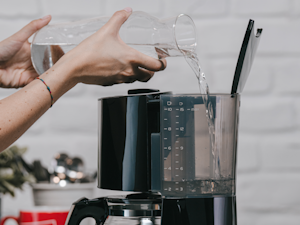 Wasser wird in den Wassertank einer schwarzen Melitta Enjoy Top Filterkaffeemaschine gefüllt