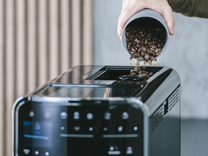 Hand füllt Kaffeebohnen in die Melitta Barista T Smart Kaffeemaschine