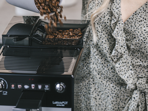 Model schüttet Melitta Kaffeebohnen in einen Melitta Kaffeevollautomaten