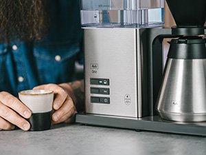 Melitta One® Therm Filterkaffeemaschine mit Isolierkanne und Tasse auf einer Küchenarbeitsplatte.