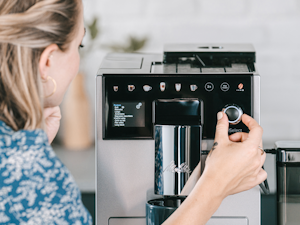Frau stellt etwas an ihrem Kaffeevollautomaten ein.