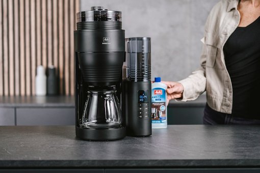 Frau stellt Melitta Anti Calc neben die AromaFresh Pro Filterkaffeemaschine
