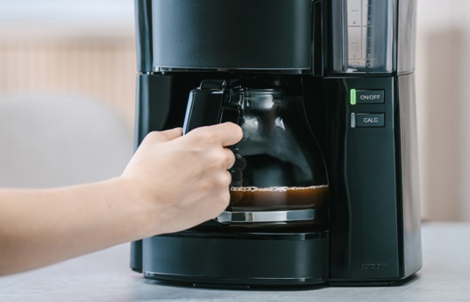 Hand nimmt die Glaskanne aus der Melitta® Look® Filterkaffeemaschine