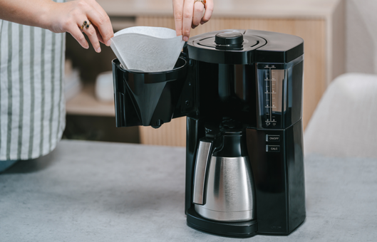 Person setzt einen Kaffeefilter in die Melitta® Look® Therm Filterkaffeemaschine ein