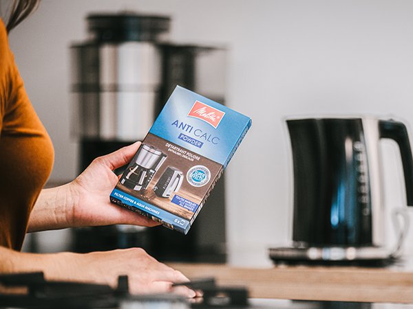 a woman stands with a packet of melitta.momscaler for a Melitta kettle and coffee machine