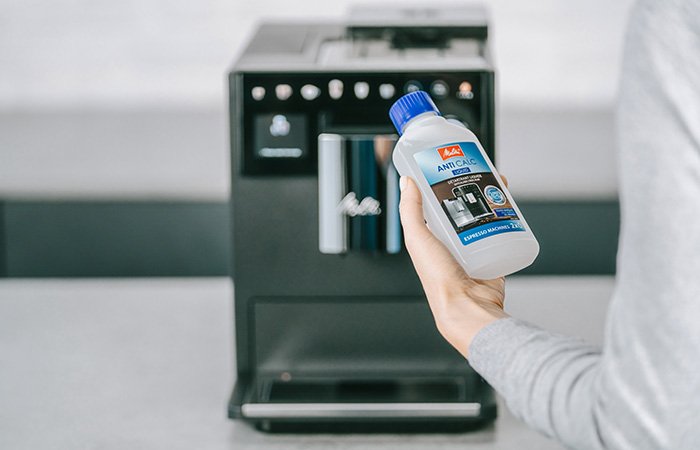 Eine Frau hält Entkalker für den Melitta Kaffeevollautomaten in der Hand