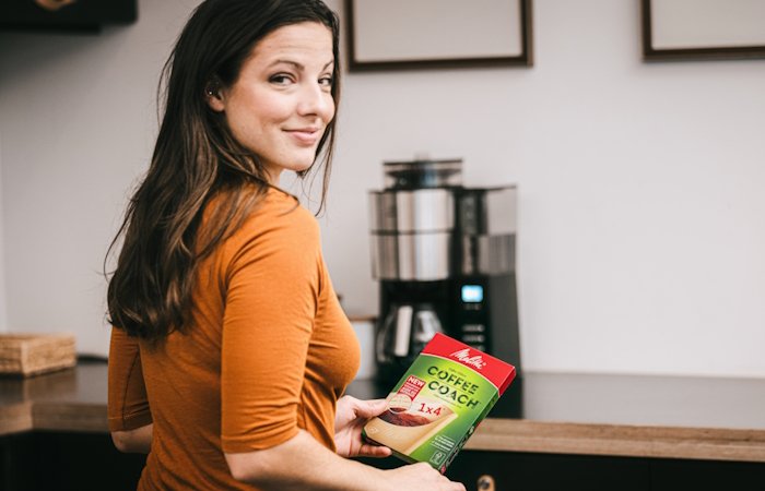 Image of a woman in her kitchen ready to try our Coffee Coach filters. 