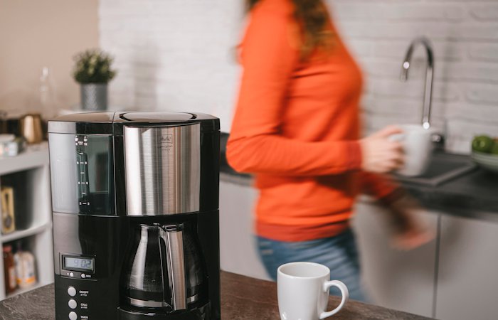 Melitta Optima® Timer Filterkaffeemaschine mit Glaskanne auf einer Küchenarbeitsplatte.
